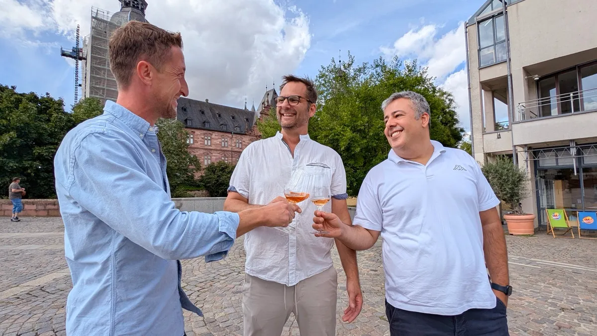 Die drei Veranstalter stoßen vor Schloss Johannisburg an